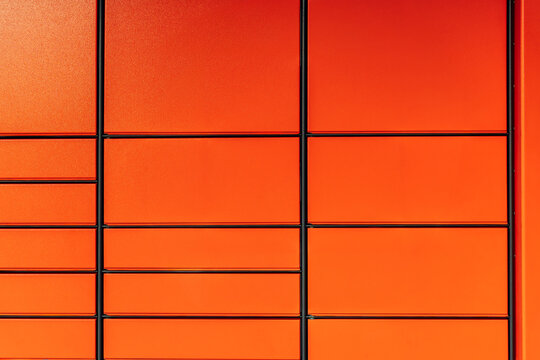 Orange parcel locker facade with geometric panel pattern