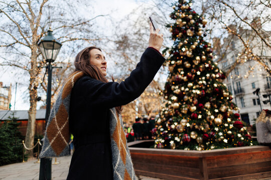 Woman capturing Christmas tree moment in London