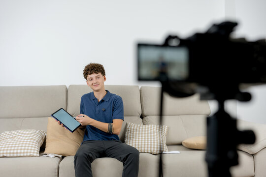 Young content creator present tablet on sofa to camera