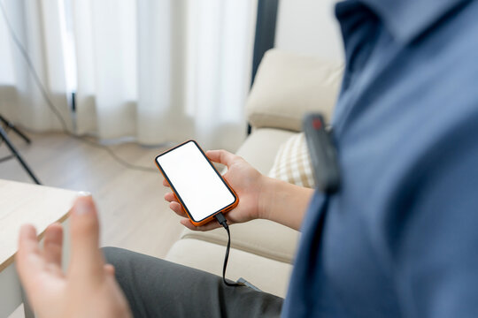 Content creator use smartphone with cable at home