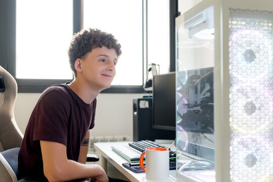 Young man at gaming computer in bright home office