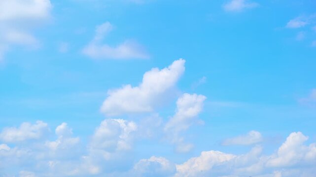 A blue sky cloud timelapse video captures fluffy white cumulus clouds forming and drifting across a vivid cyan blue sky, revealing gentle wind movement, warm daylight and calm fair weather conditions.