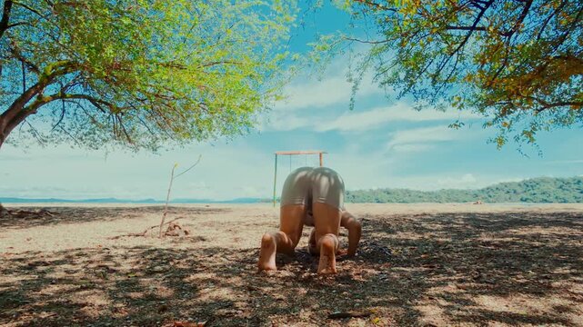 Flexible woman performing a headstand split yoga pose on a beach