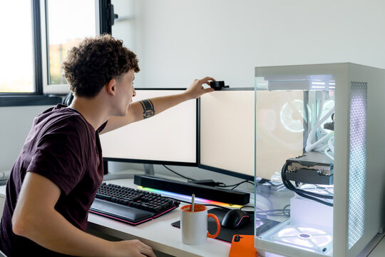 Young man adjust webcam beside gaming computer workstation