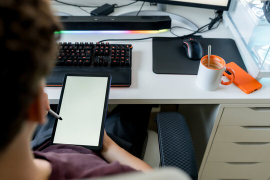 Young man use tablet with AI tools at gaming computer