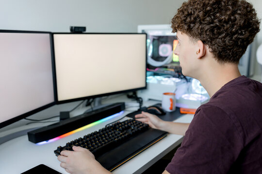 Young man use gaming computer with dual monitor setup