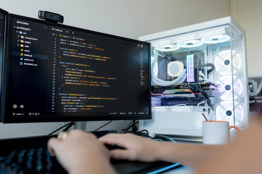 Software developer coding at computer with gaming pc