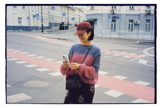 Woman standing on a city street checking her smartphone