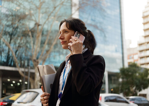 Woman on Phone in City Near Office Buildings During the Day