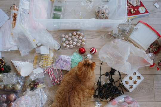 Ginger cat lying among Christmas decorations and ornaments flat lay