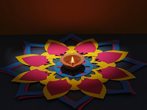 Diwali diya illuminates a colorful paper mandala