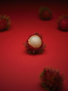 Close-up of a vibrant red rambutan fruit, cut open