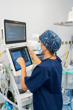 Anesthesiologist adjusting medical equipment in operating room