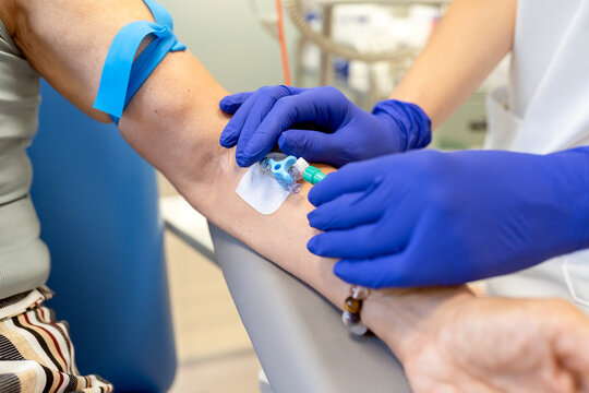 Nurse drawing blood from patient arm with iv catheter