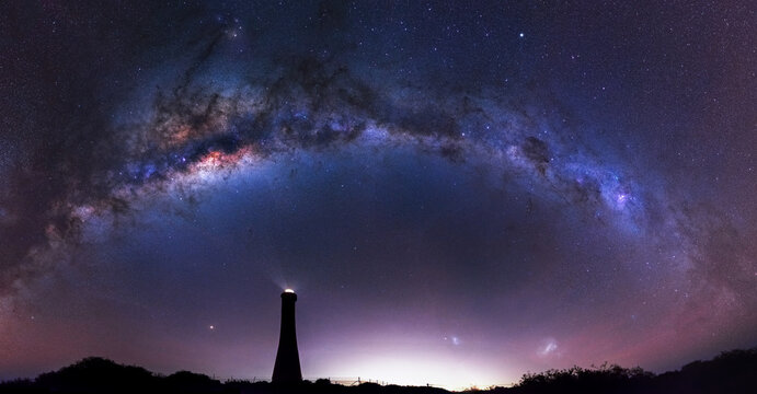 Milky Way arching over a lighthouse