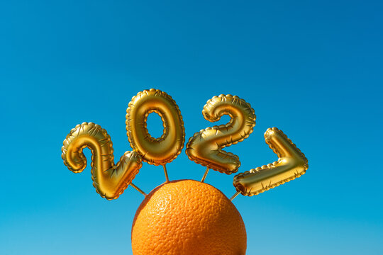 Gold balloon arch over orange on blue background