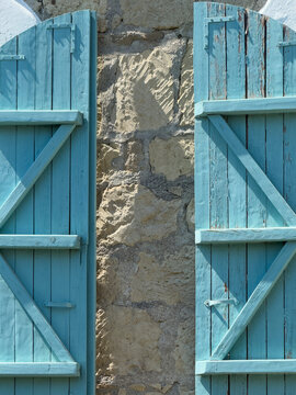 Weathered blue wooden shutters on rustic stone facade