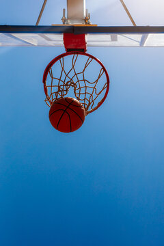 Basketball Passing Through Hoop Against Blue Sky