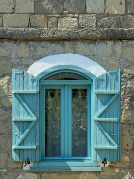 Turquoise shuttered window on rustic stone facade