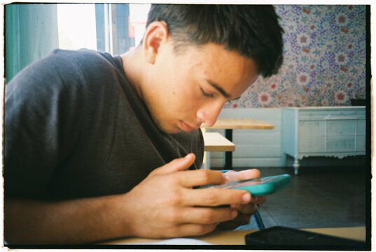Teenager Using a Phone in a Cafe During the Day