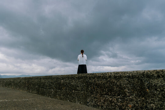 Facing the Storm: Woman Standing on the Coast