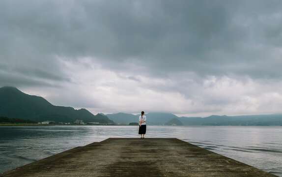 Facing the Storm: Woman Standing on the Coast