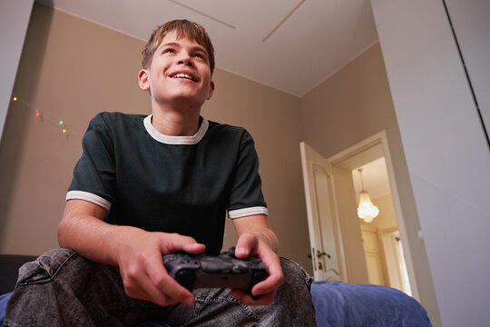 Happy teen gamer playing video games with controller