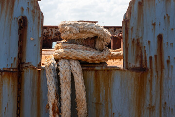Rusted Mooring Rope Wrapped Around Single Bollard on Grey Ship Hull in Crete © imagoDens