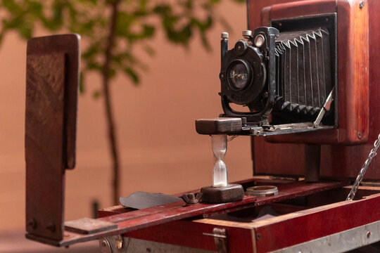Vintage wooden bellows camera with hourglass on table