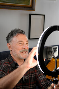Mature man create remote work video with ring light