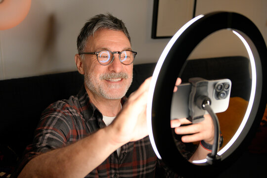 Mature man use smartphone and ring light for remote work