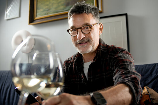 Mature man work remotely from home with wine glass