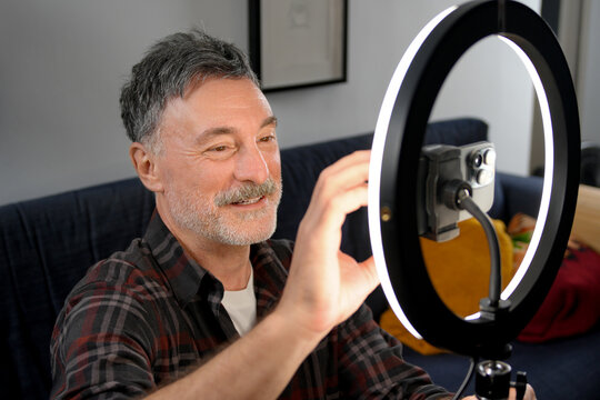 Mature man adjust smartphone camera for remote work video