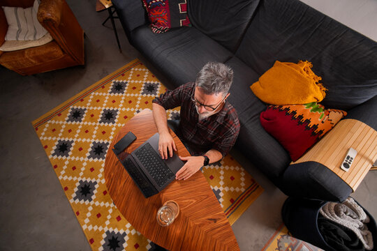 Mature man working remotely on laptop at home