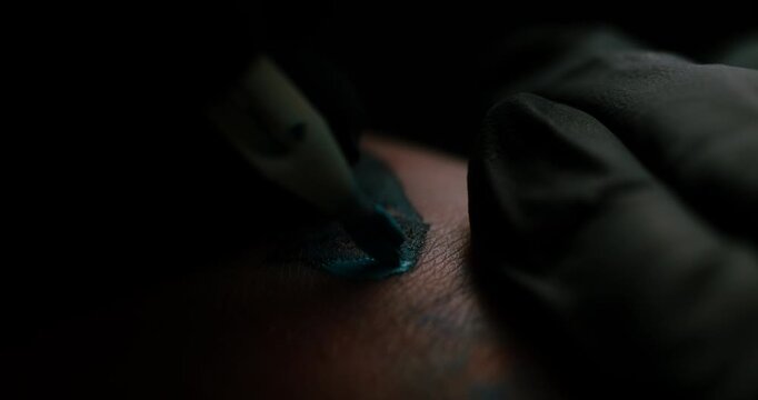 Tattoo artist packing color pigment into skin in slow motion