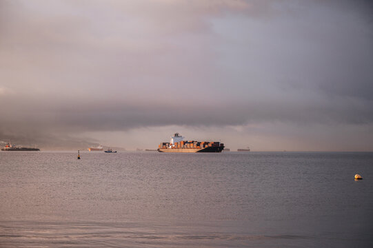 Container ship off Gibraltar under dramatic overcast sky
