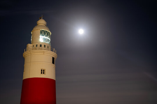 Gibraltar lighthouse beneath a glowing full moon at night