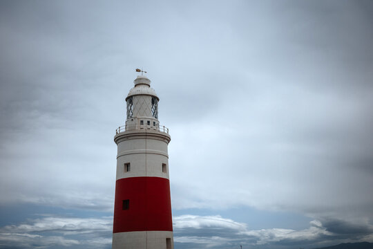 Red and white lighthouse at Gibraltar under cloudy sky
