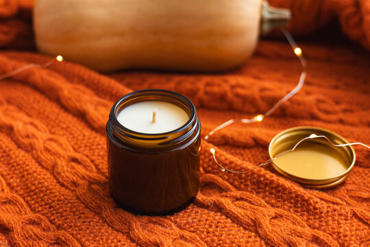 Handmade candle on orange knitted autumn background