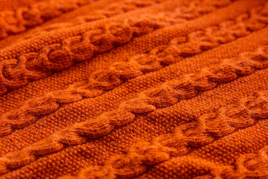 Orange cable knit sweater texture close-up background