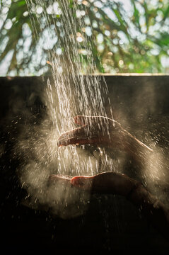 Hands under sunlit water shower outdoors
