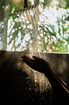 Hands under outdoor shower in warm sunlight