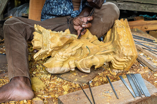 Artisan carve wooden dragon sculpture in traditional workshop