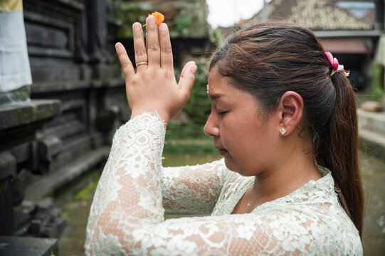 Balinese woman praying with flower offering at temple