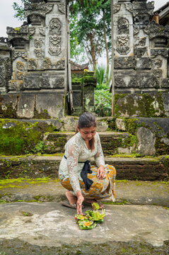 Balinese woman place offering at Hindu temple gate