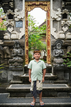 Balinese boy standing at ornate Hindu temple entrance