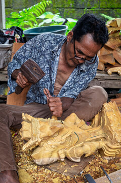 Indonesian artisan carve wooden dragon sculpture by hand