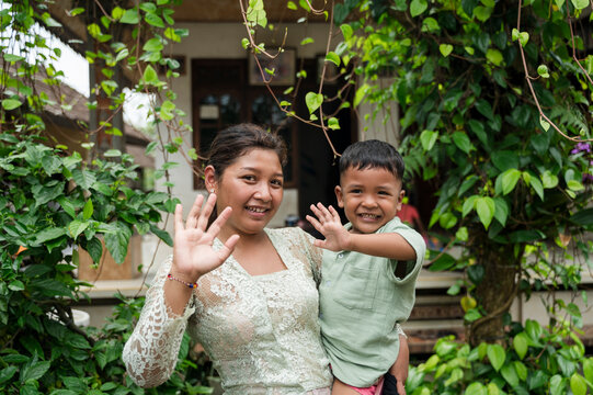 Smiling mother and son wave outdoors in Bali
