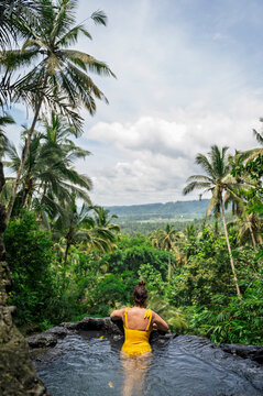 Woman in infinity pool overlooking Bali tropical forest