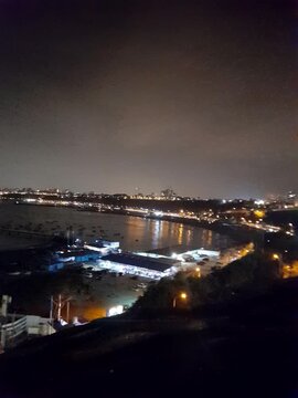 Panoramic night view of illuminated coastal bay harbor and city lights